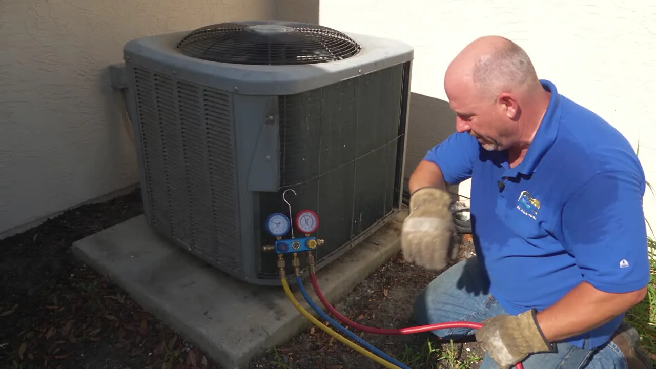 A technician reads refrigerant gauges connected to an outdoor AC unit